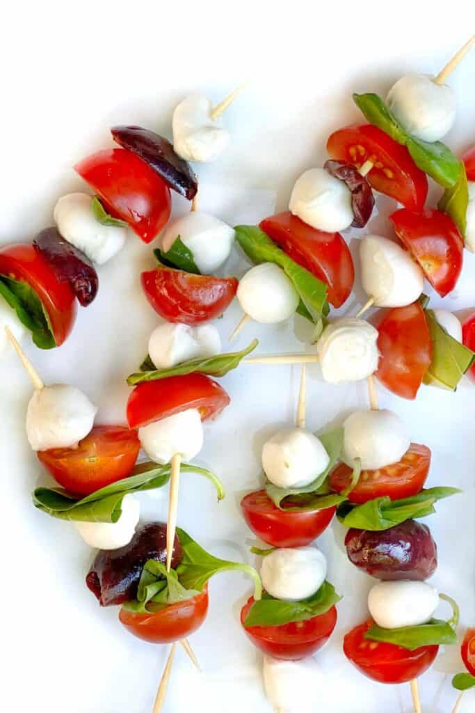 Assorted summer appetizers including cold dips, caprese skewers, mini grilled cheese, and smoked salmon, perfect for any summer dinner party or bbq.