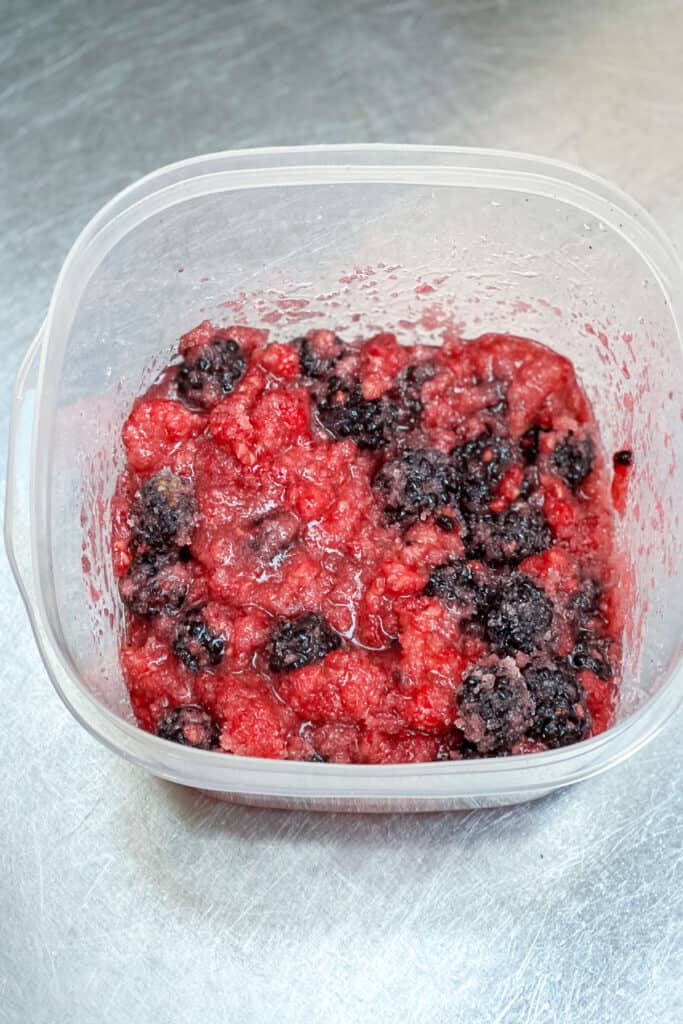 fully mixed berries and sugar in a plastic container