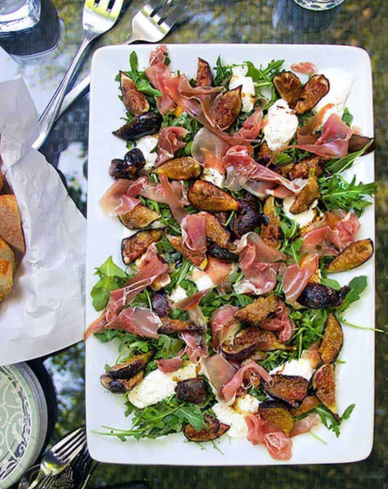 Rectangular platter topped with grilled figs, prosciutto and burrata
